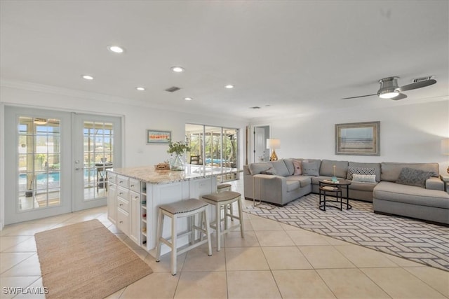 kitchen with crown molding, a breakfast bar, white cabinetry, a kitchen island, and french doors