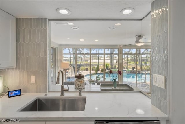 kitchen with white cabinetry, sink, plenty of natural light, and light stone countertops