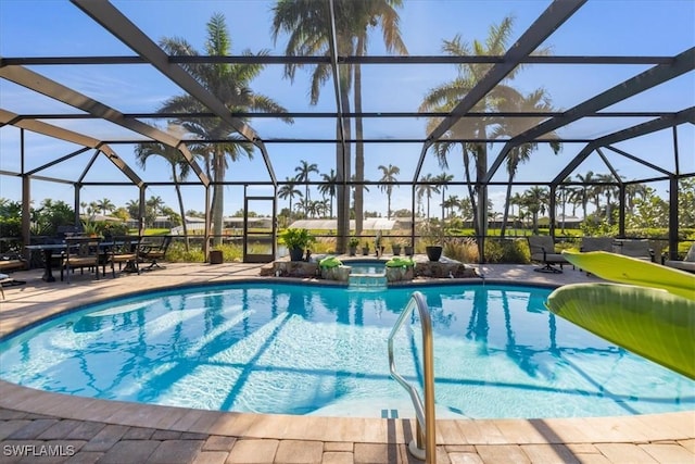 view of pool with a patio area, an in ground hot tub, and glass enclosure