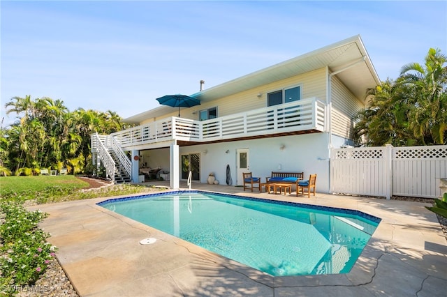 back of house with stairway, fence, an outdoor pool, and a patio