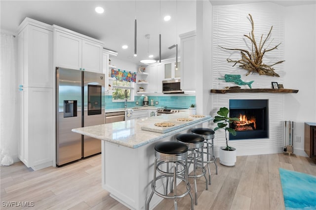 kitchen with tasteful backsplash, white cabinetry, stainless steel appliances, and light stone counters