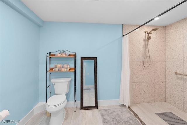 bathroom with baseboards, a tile shower, and toilet