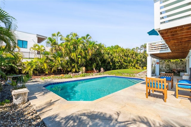 outdoor pool with a patio area, fence, and an outdoor hangout area