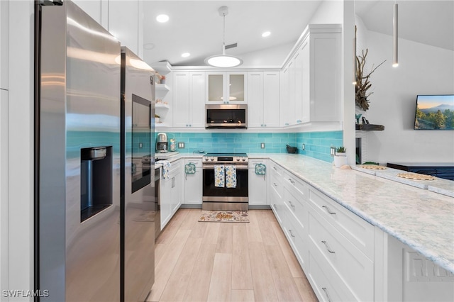 kitchen featuring light wood finished floors, light stone counters, stainless steel appliances, white cabinetry, and backsplash