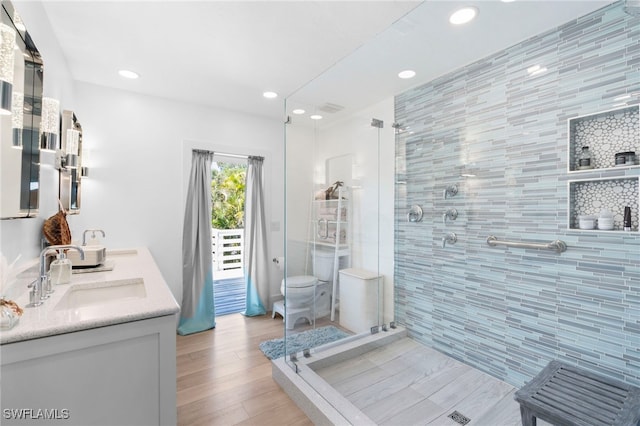 bathroom with recessed lighting, wood finished floors, a sink, a shower stall, and double vanity