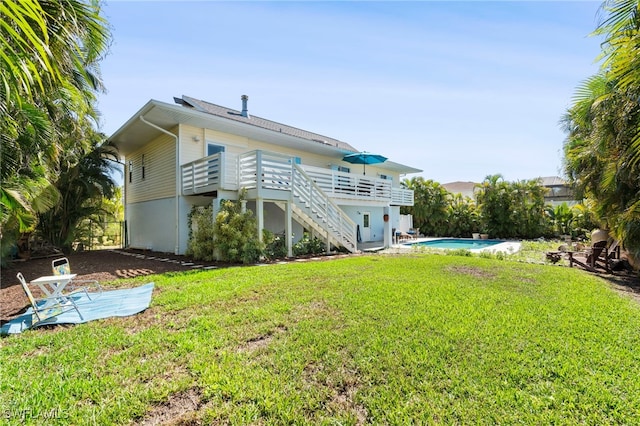 back of property featuring a wooden deck, stairway, an outdoor pool, and a yard