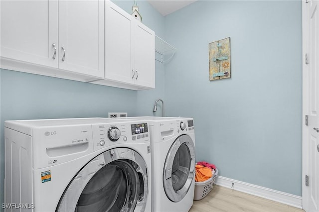 laundry area featuring cabinets, washer and dryer, and light wood-type flooring