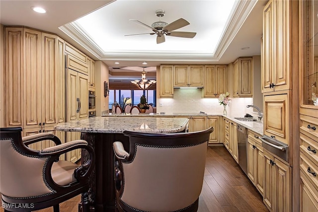 kitchen featuring black appliances, a breakfast bar, sink, and a tray ceiling