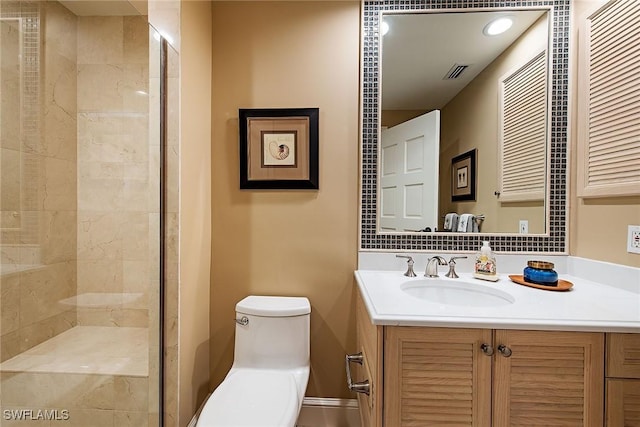 bathroom featuring vanity, a tile shower, and toilet