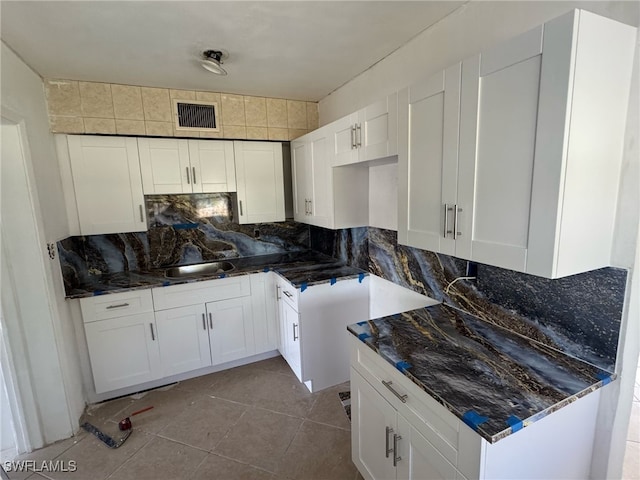 kitchen with white cabinetry, visible vents, backsplash, and a sink