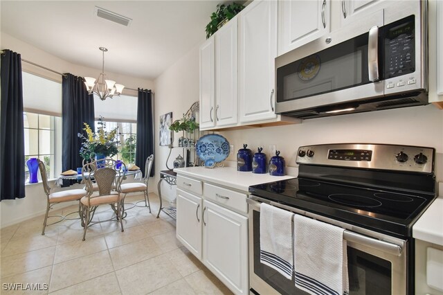 kitchen featuring pendant lighting, white cabinets, light tile patterned floors, stainless steel appliances, and an inviting chandelier