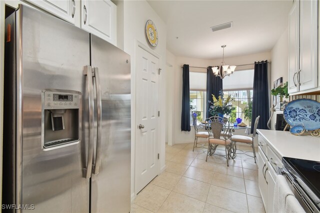 kitchen with appliances with stainless steel finishes, white cabinetry, hanging light fixtures, an inviting chandelier, and light tile patterned flooring