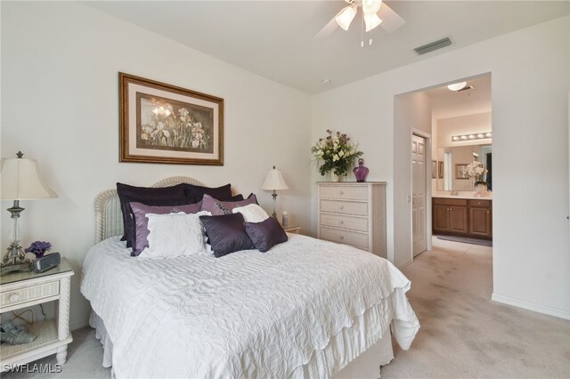 bedroom with ceiling fan, ensuite bath, and light carpet