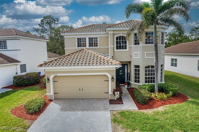 mediterranean / spanish house with a tiled roof, an attached garage, decorative driveway, a front lawn, and stucco siding