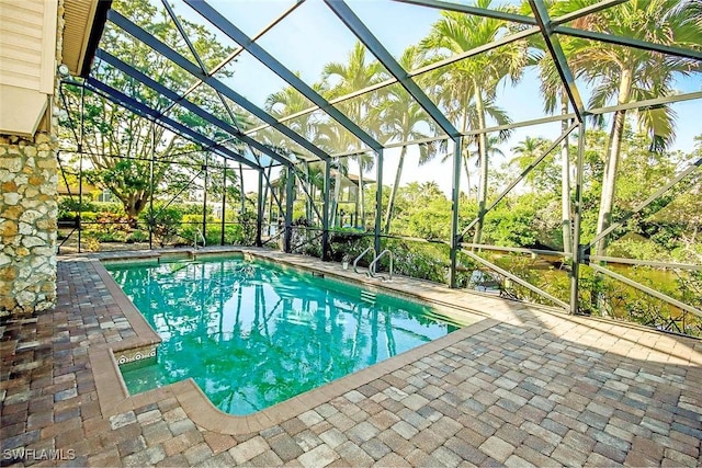 view of swimming pool with glass enclosure and a patio area