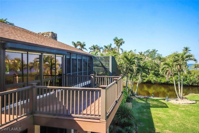 wooden terrace with a water view, glass enclosure, and a yard