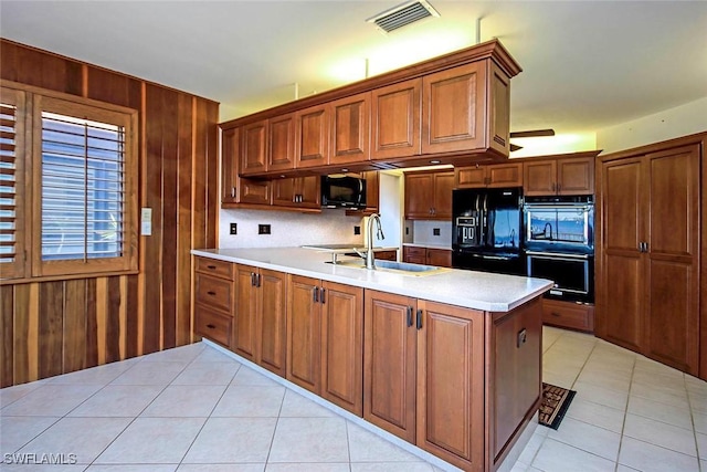 kitchen featuring light tile patterned floors, sink, wood walls, and black appliances