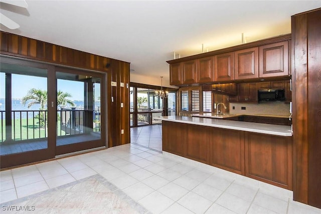 kitchen with backsplash, a notable chandelier, pendant lighting, kitchen peninsula, and wooden walls