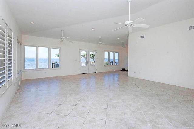 unfurnished living room featuring a water view, vaulted ceiling, ceiling fan, and light tile patterned floors