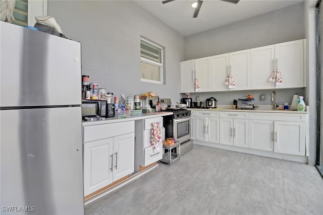 kitchen with appliances with stainless steel finishes, a sink, a ceiling fan, and white cabinets