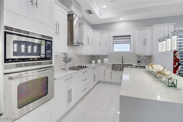 kitchen featuring visible vents, a sink, wall chimney exhaust hood, and white cabinetry