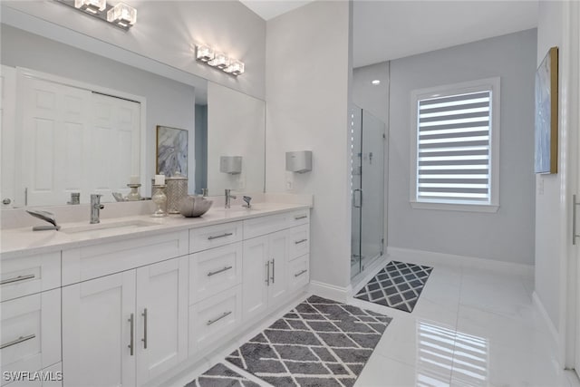 full bathroom featuring double vanity, a stall shower, baseboards, and a sink