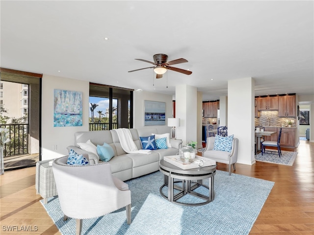 living room featuring light wood-style flooring, a ceiling fan, and recessed lighting