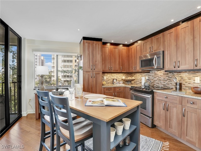 kitchen with light wood-type flooring, brown cabinetry, tasteful backsplash, and stainless steel appliances