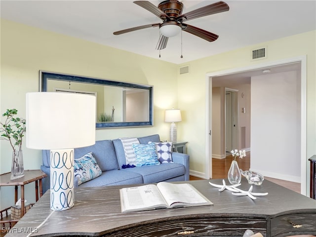 living area with baseboards, visible vents, and ceiling fan