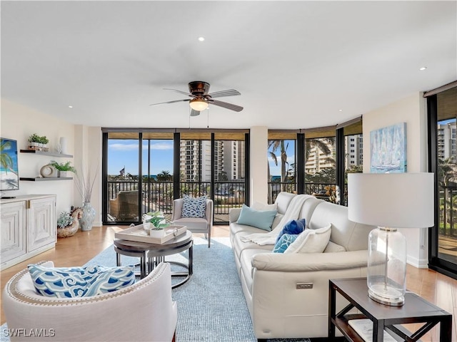 living room featuring ceiling fan, wood finished floors, and floor to ceiling windows