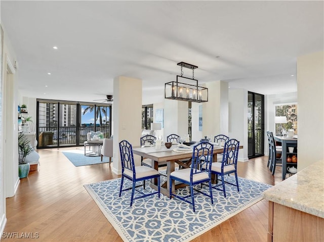 dining area with light wood-style flooring, recessed lighting, ceiling fan with notable chandelier, baseboards, and floor to ceiling windows