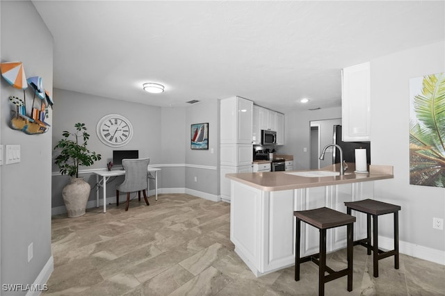 kitchen featuring white cabinetry, appliances with stainless steel finishes, sink, and kitchen peninsula