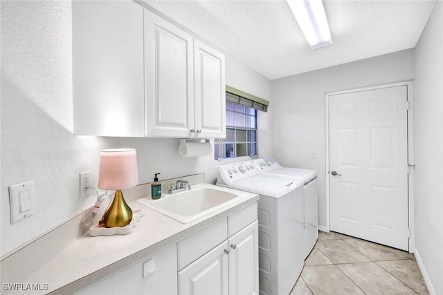 clothes washing area featuring cabinet space, independent washer and dryer, a textured ceiling, a sink, and light tile patterned flooring