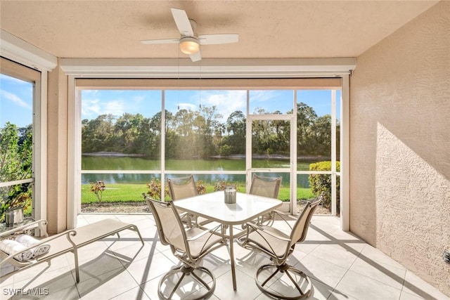 unfurnished sunroom featuring a ceiling fan and a water view