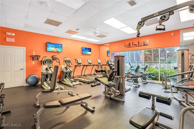 gym with visible vents, a paneled ceiling, a wealth of natural light, and a ceiling fan