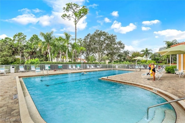 community pool with fence and a patio