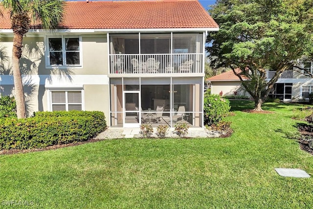 back of house with a sunroom, a lawn, a tiled roof, and stucco siding