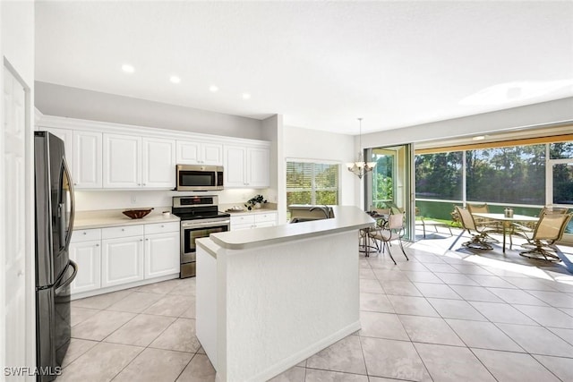 kitchen featuring light tile patterned floors, a notable chandelier, white cabinetry, light countertops, and appliances with stainless steel finishes