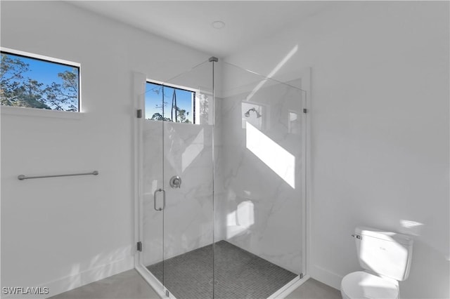 bathroom featuring a shower with shower door and toilet