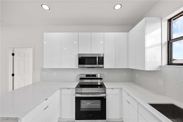 kitchen featuring light stone counters, appliances with stainless steel finishes, decorative backsplash, and white cabinets