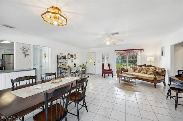 tiled dining room with ceiling fan with notable chandelier