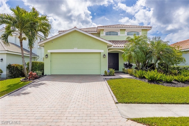 mediterranean / spanish home with a garage, decorative driveway, a tile roof, and stucco siding