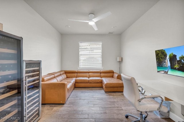 office space with beverage cooler, ceiling fan, and light wood-type flooring