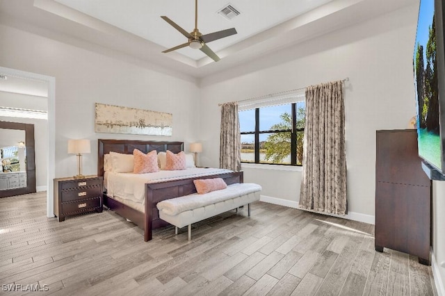 bedroom featuring ceiling fan, a raised ceiling, and light hardwood / wood-style flooring