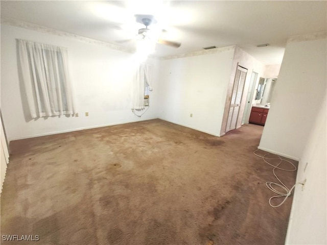 empty room with ceiling fan, dark carpet, and visible vents