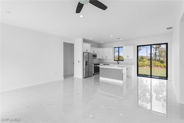 kitchen with ceiling fan, a center island, white cabinets, and appliances with stainless steel finishes