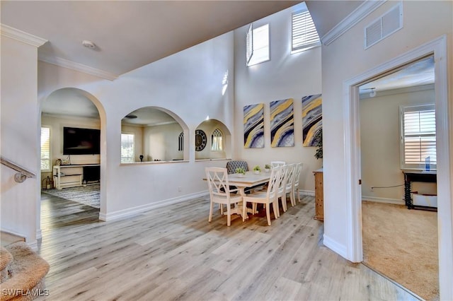 dining area with ornamental molding and light hardwood / wood-style floors