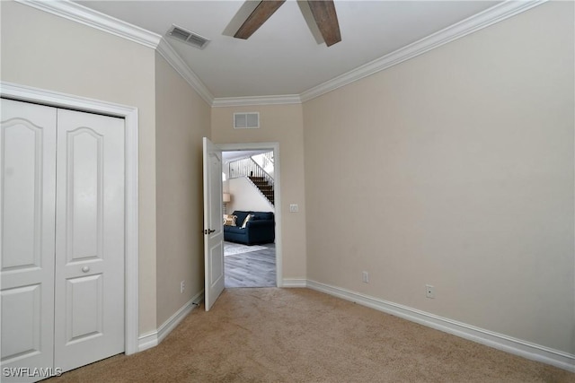 unfurnished bedroom with crown molding, ceiling fan, a closet, and light carpet