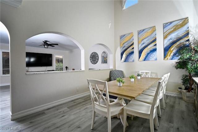 dining room with hardwood / wood-style floors, a towering ceiling, ornamental molding, and ceiling fan