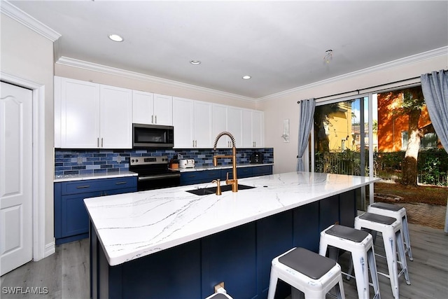 kitchen with white cabinetry, sink, stainless steel appliances, and a center island with sink